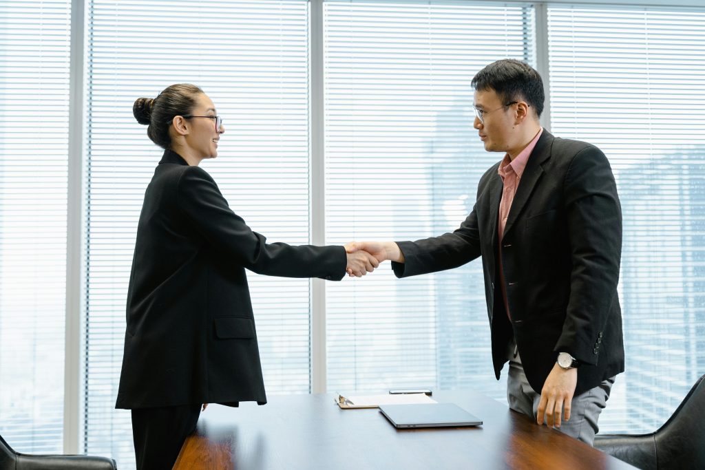 pexels-photo-7643738-7643738 Two business professionals exchange a handshake in a modern office, sealing a deal.